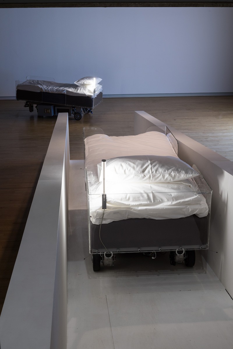 Two Roaming Beds, 2015 Acciaio dipinto, motori elettrici, nylon stampato 3D, pneumatici in gomma, cavi, componenti elettrici, lampadina LED, vetro acrilico, caricatori per cellulari, materassi, lino, inchiostro, penne 2 parti, ciascuna: ca. 130 x 210 x 100 cm Foto: Elzbieta Bialkowska, 2015 Courtesy dell’artista Prodotto in collaborazione con Hayward Gallery, Londra, Bonniers Konsthall, Stoccolma  e Pirelli HangarBicocca, Milano