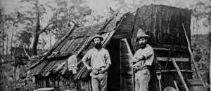 Gold miners outside a bark hut, Queensland, ca. 1870 (7464840500)