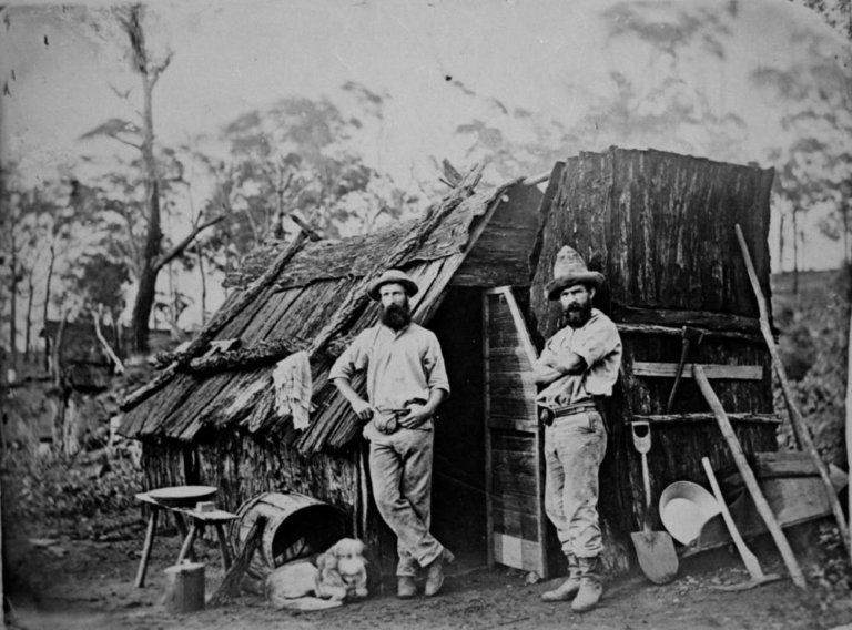 Gold miners outside a bark hut, Queensland, ca. 1870 (7464840500)