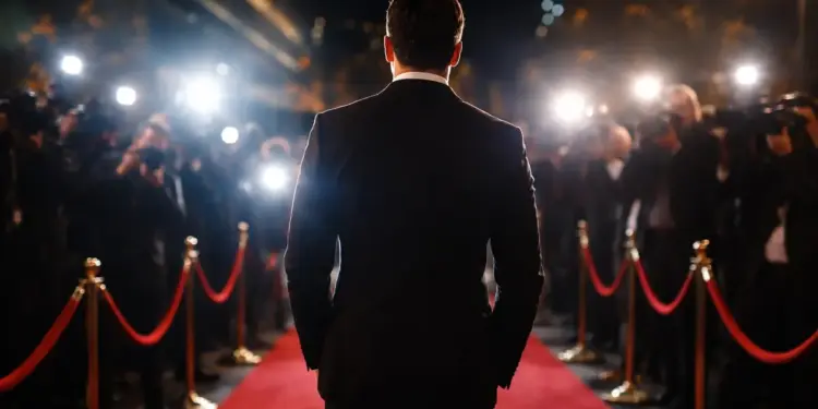 Celebrità cammina su tappeto rosso in mezzo ai fotografi