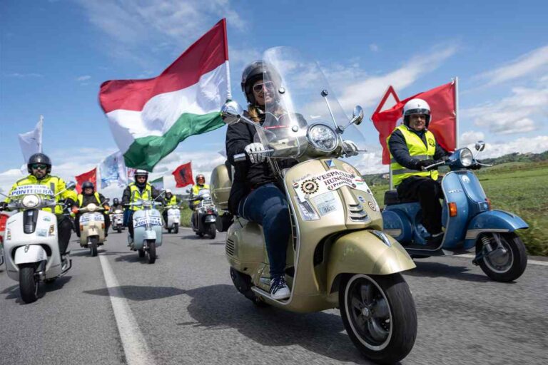 Immagine di un raduno Vespa con vespisti e bandiere tricolori