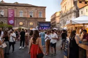 Folla in una piazza di Roma con palco “Estate Romana” e stand gastronomici al tramonto