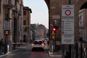Auto in coda al varco ZTL con cartelli “zona traffico limitato” e display “ZTL non attiva” al tramonto a Roma