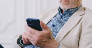 Anziano con telefono in mano mentre digita un numero