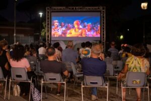 Una immagine di una arena esterna per la visione di film, con spettatori seduti di spalle.