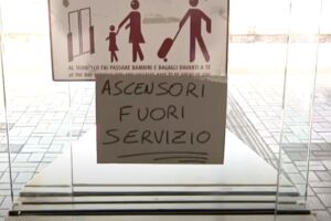 Cartello scritto a mano con la scritta ascensori fuori servizio affisso su una porta a vetri in stazione