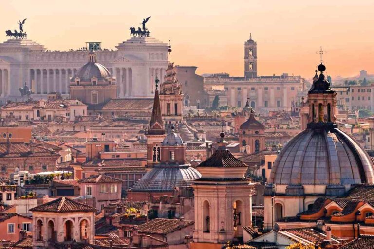 Panorama del centro storico di Roma al tramonto con cupole di chiese, tetti e il Vittoriano sullo sfondo