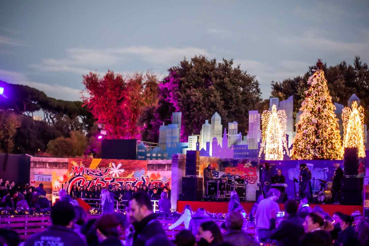 Concerto natalizio all'aperto con coro, skyline luminoso e albero di Natale illuminato