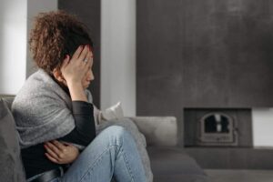 Donna incinta seduta su un divano, triste.