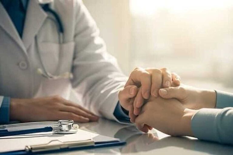 Un medico stringe la mano ad un paziente in un momento di difficoltà per incoraggiarlo