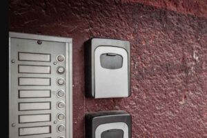 Due cassette di sicurezza per chiavi (key box) montate sul muro accanto a un citofono condominiale, simbolo degli affitti brevi Airbnb