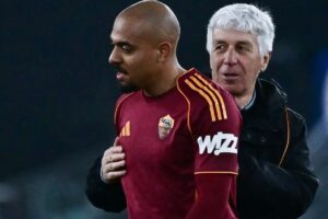 Malen, calciatore della Roma in maglia amaranto con il mister Gasperini alle spalle durante una partita