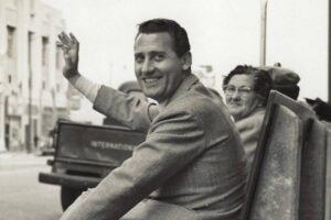 Alberto Sordi giovane sorride e saluta in una foto in bianco e nero, anni Cinquanta