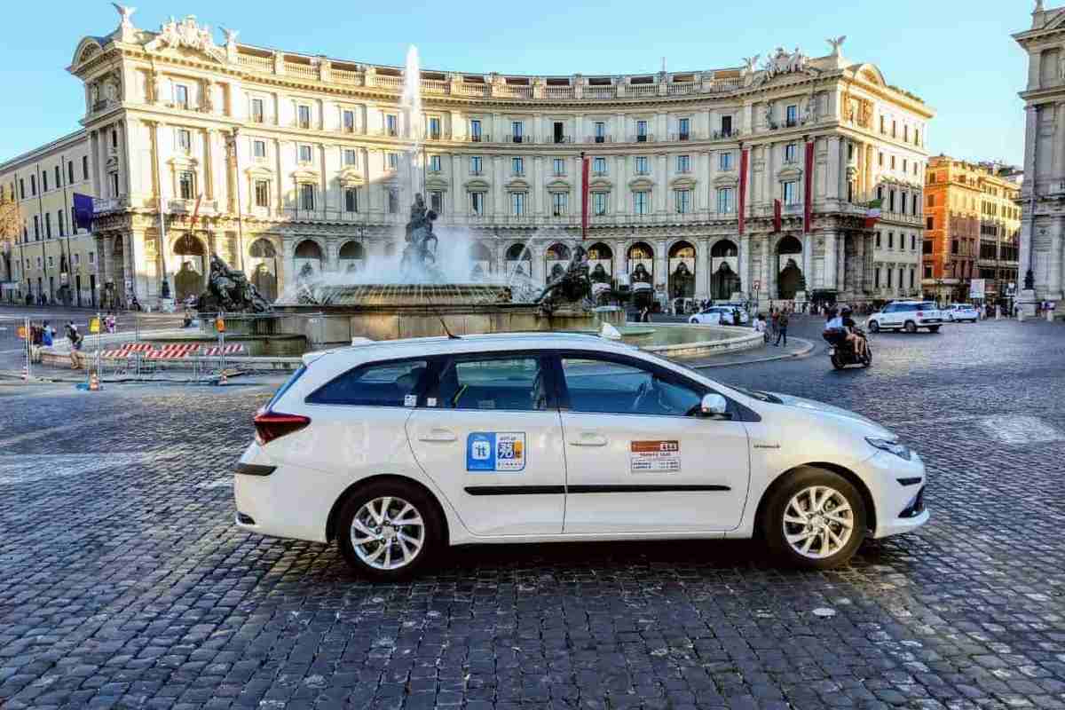 Taxi bianco parcheggiato in Piazza della Repubblica a Roma con la Fontana delle Naiadi e il palazzo dell'Esedra sullo sfondo