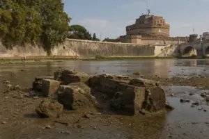 Blocchi di pietra affiorati nel Tevere in secca con Castel Sant’Angelo sullo sfondo a Roma