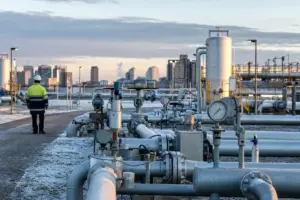 Impianto di stoccaggio e distribuzione del gas con tubazioni e manometri ghiacciati, operaio di spalle e skyline sullo sfondo